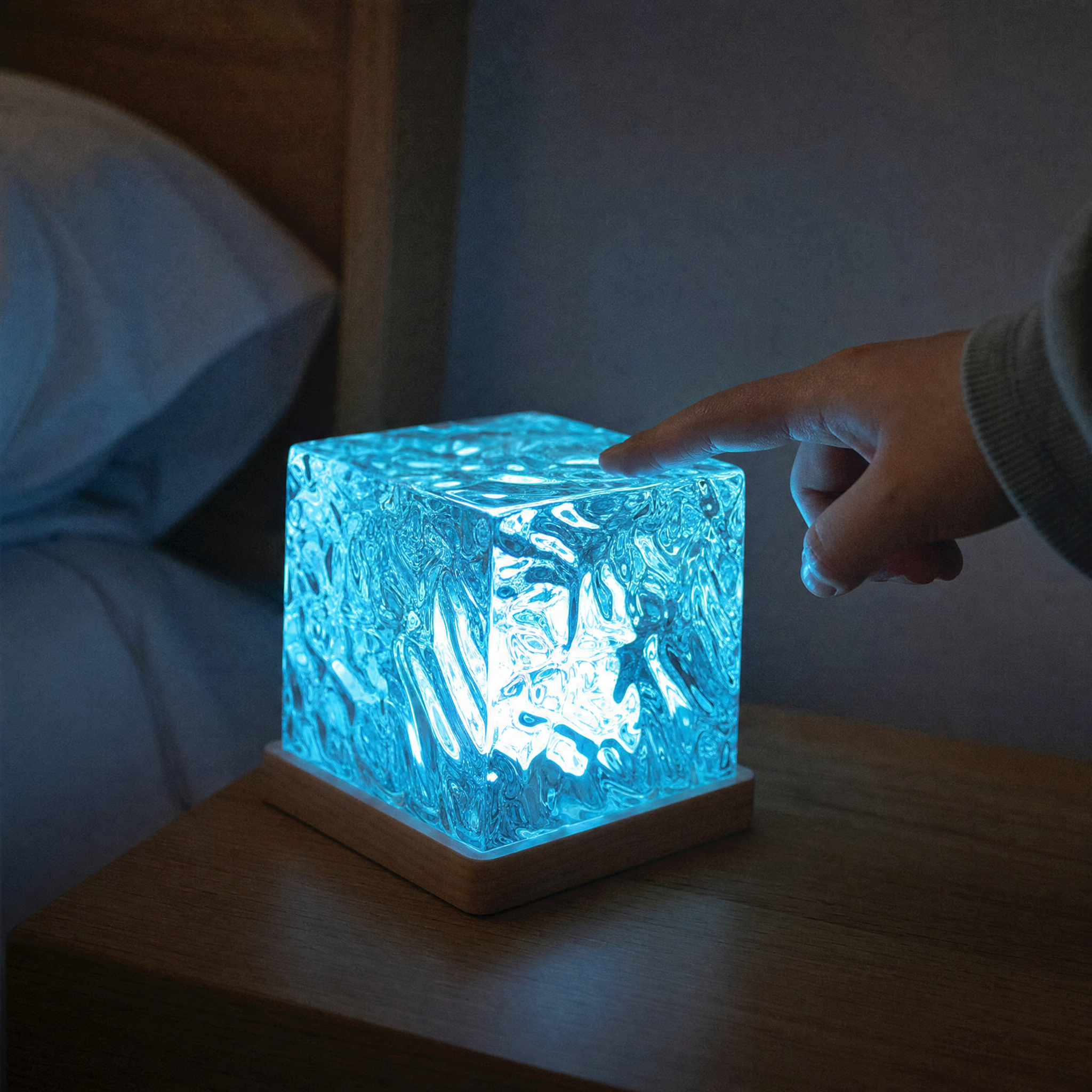 Close-up of the rippled acrylic projector cube glowing blue on its wooden base