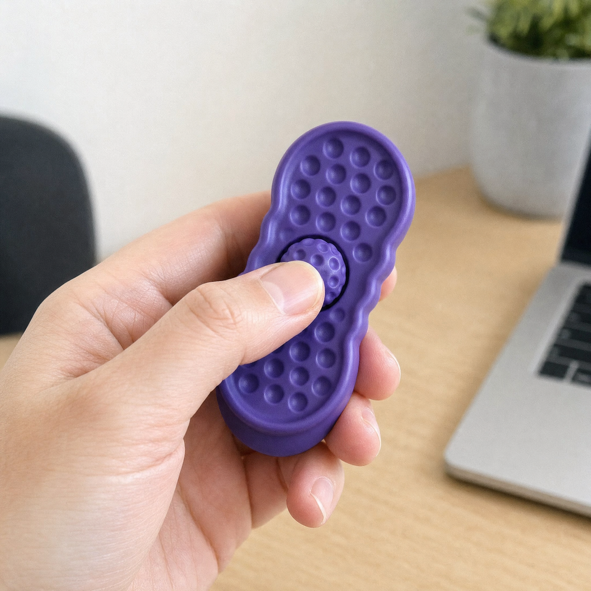 A hand holding the purple rotating stone slider, thumb on the central spinning disc